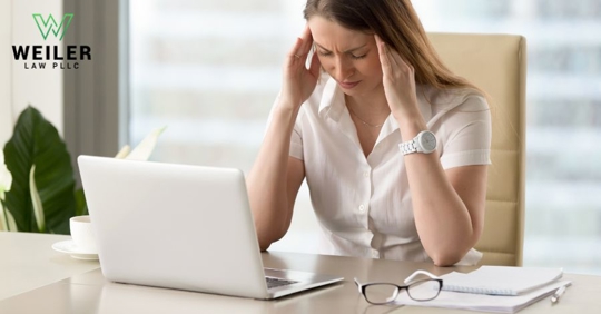 female employee holding her head